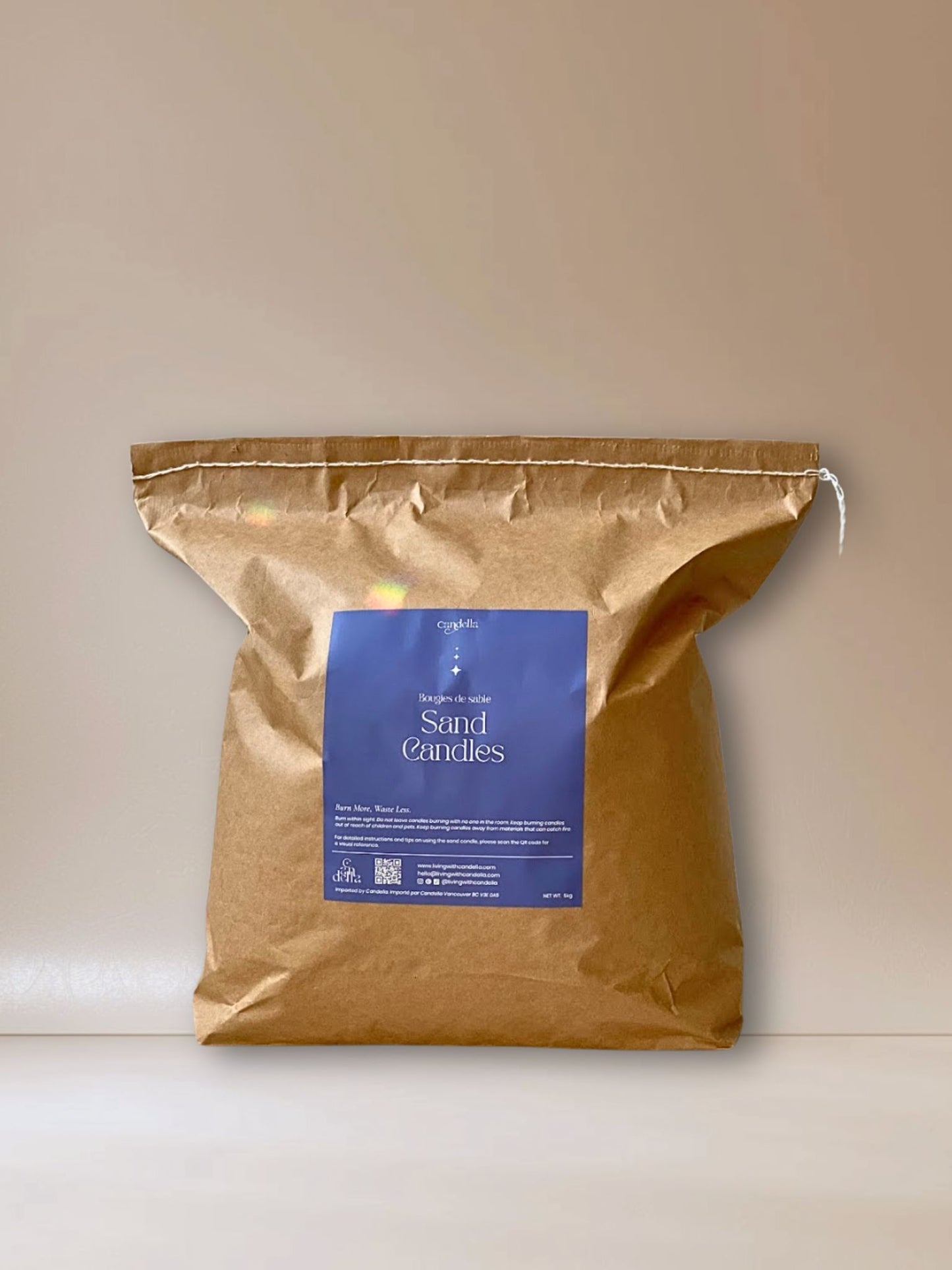 A kraft 5kg bag of sand candle wax labeled "Candella Sand Candles" with blue packaging and text in English and French, designed for event vendors for a sustainable candle experience.