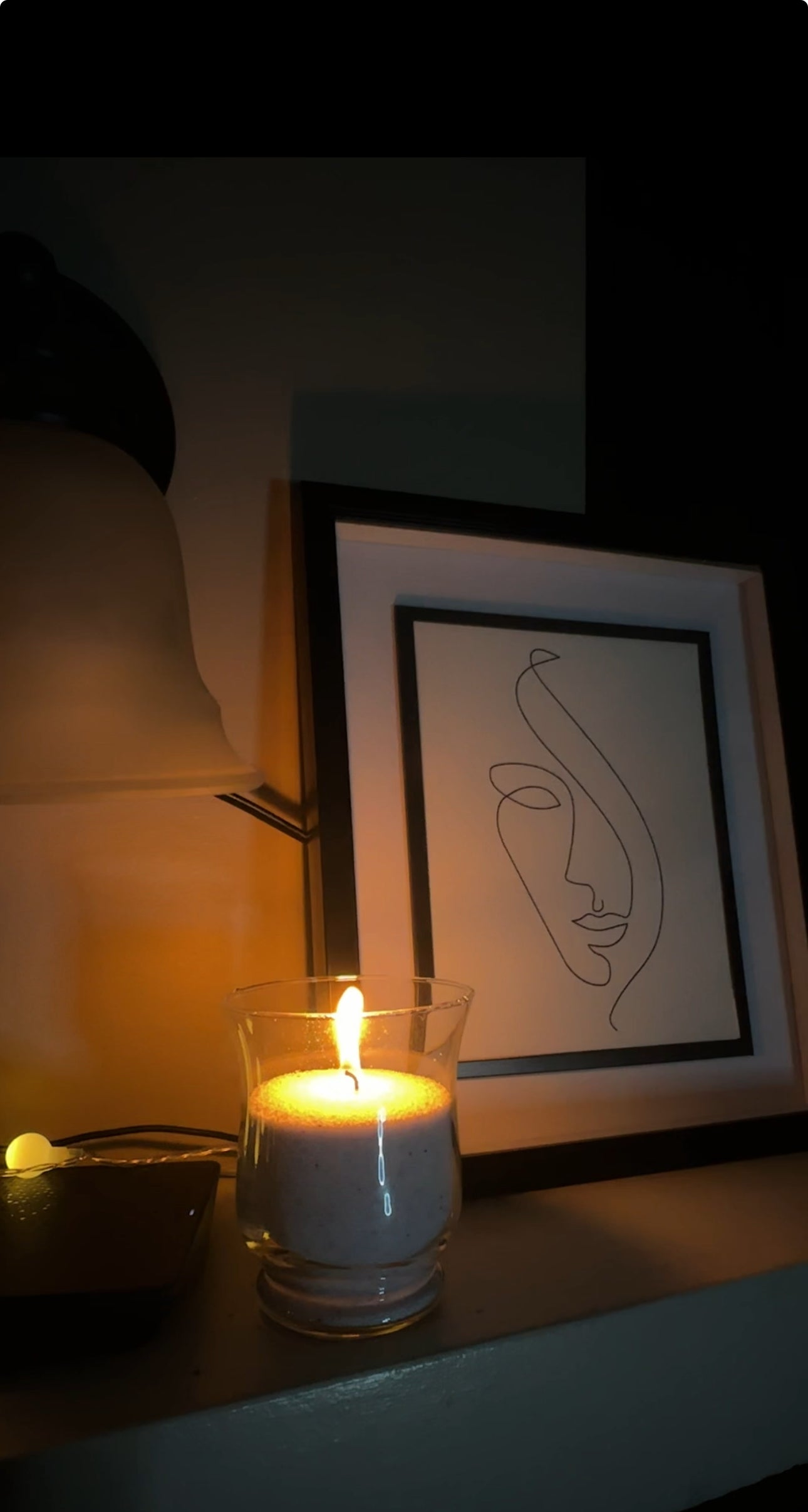 A candle filled with Candella's sand wax, placed in an aesthetic corner of the bedroom.