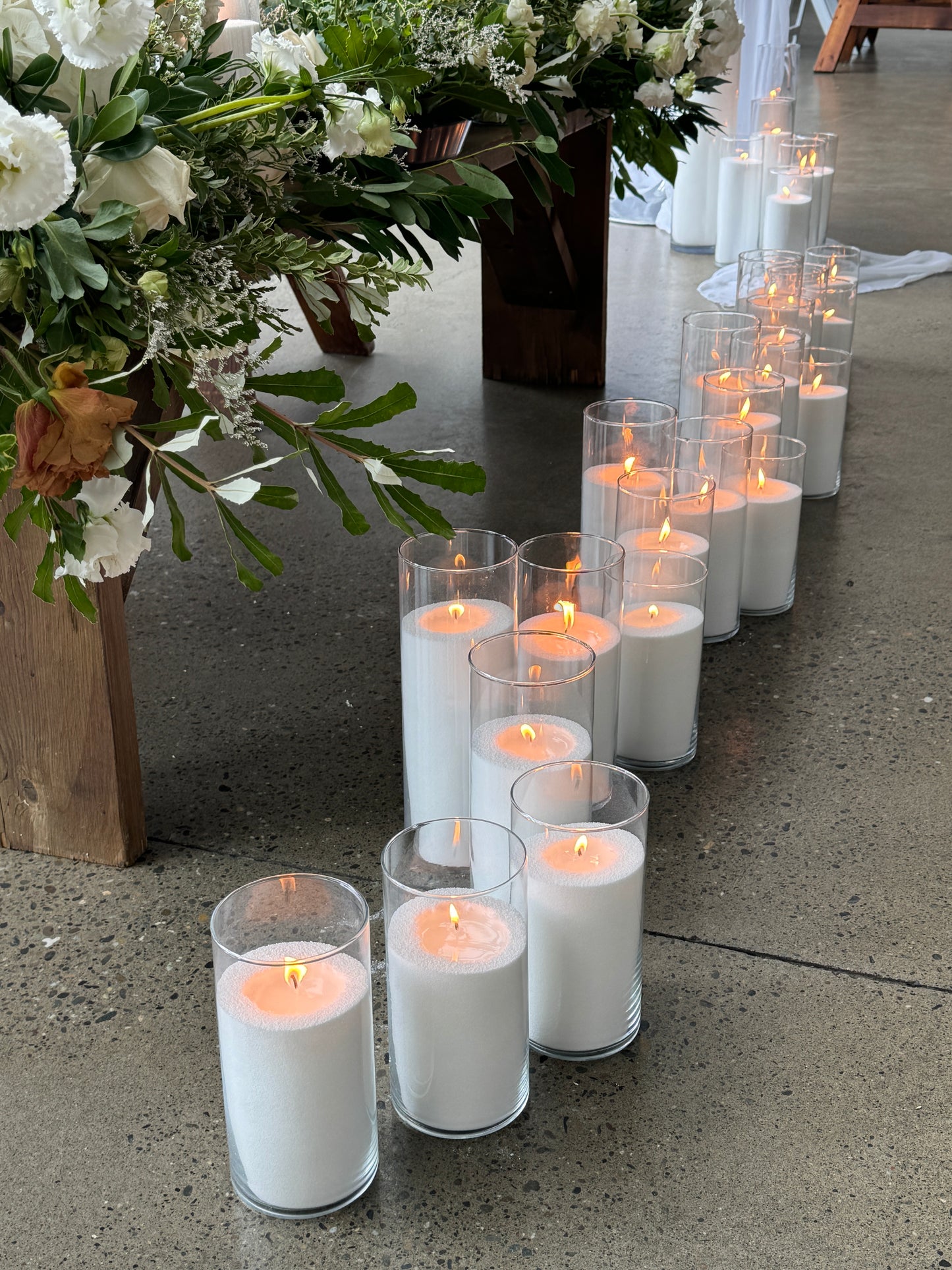 A row of glass vessels with lit candella sand candles, creating a romantic ambiance.