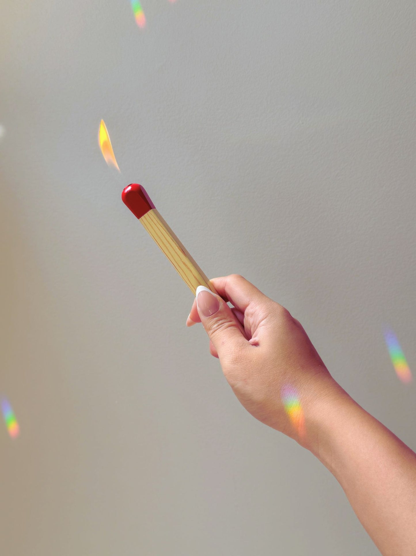 A hand holding the matchstick lighter with the flame on.