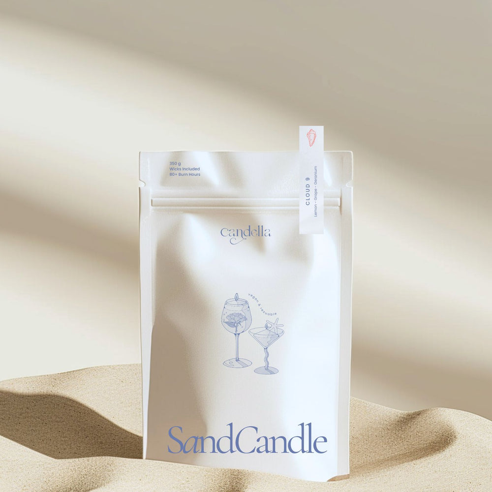 A product image of Candella's Sand Candle. The minimalist, cream-coloured pouch features a subtle illustration of two cocktail glasses with text that reads "Vegan & Reusable." A small label at the top right corner of the package indicates the scent "CLOUD 9" with notes of "Lemon - Grape - Geranium."