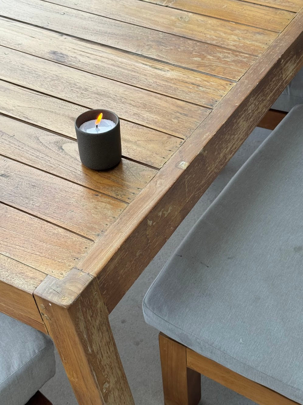 A candle in a brown cup placed on a dining table.