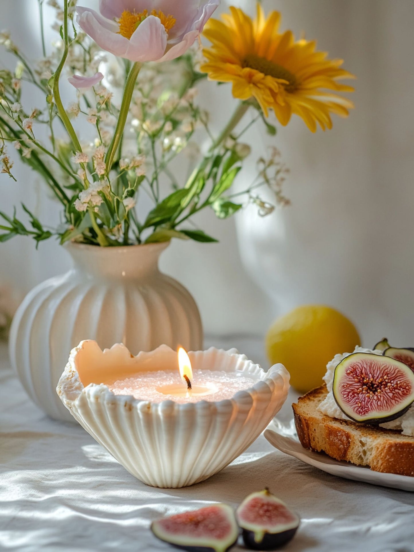 A kitchen tabletop scene featuring a lit pastel pink Candella Sand Candle in a unique white seashell vessel.